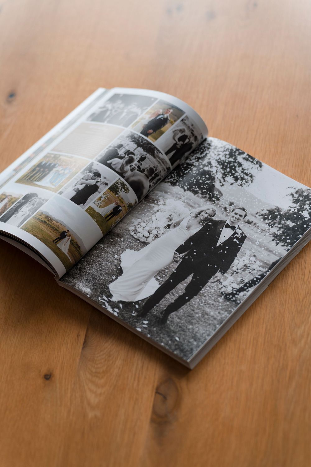 Wedding album displayed on wooden table showing black and white photographs spread across pages.