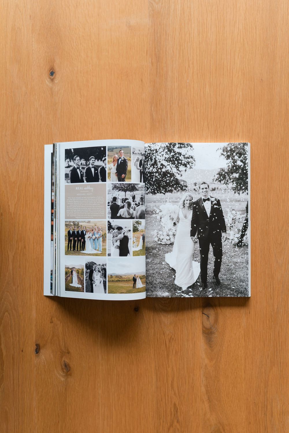 An opened photo album displaying black and white vintage photographs laid flat on a wooden table surface.