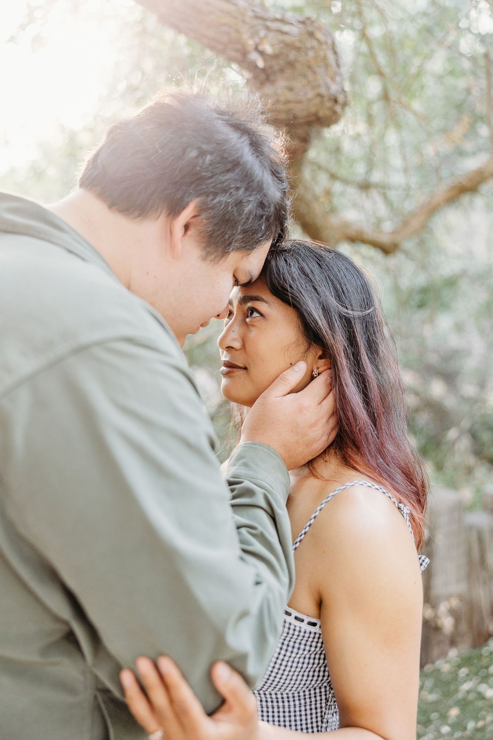 A romantic couple embraces outdoors while sharing intimate moments during a photoshoot in a natural setting.