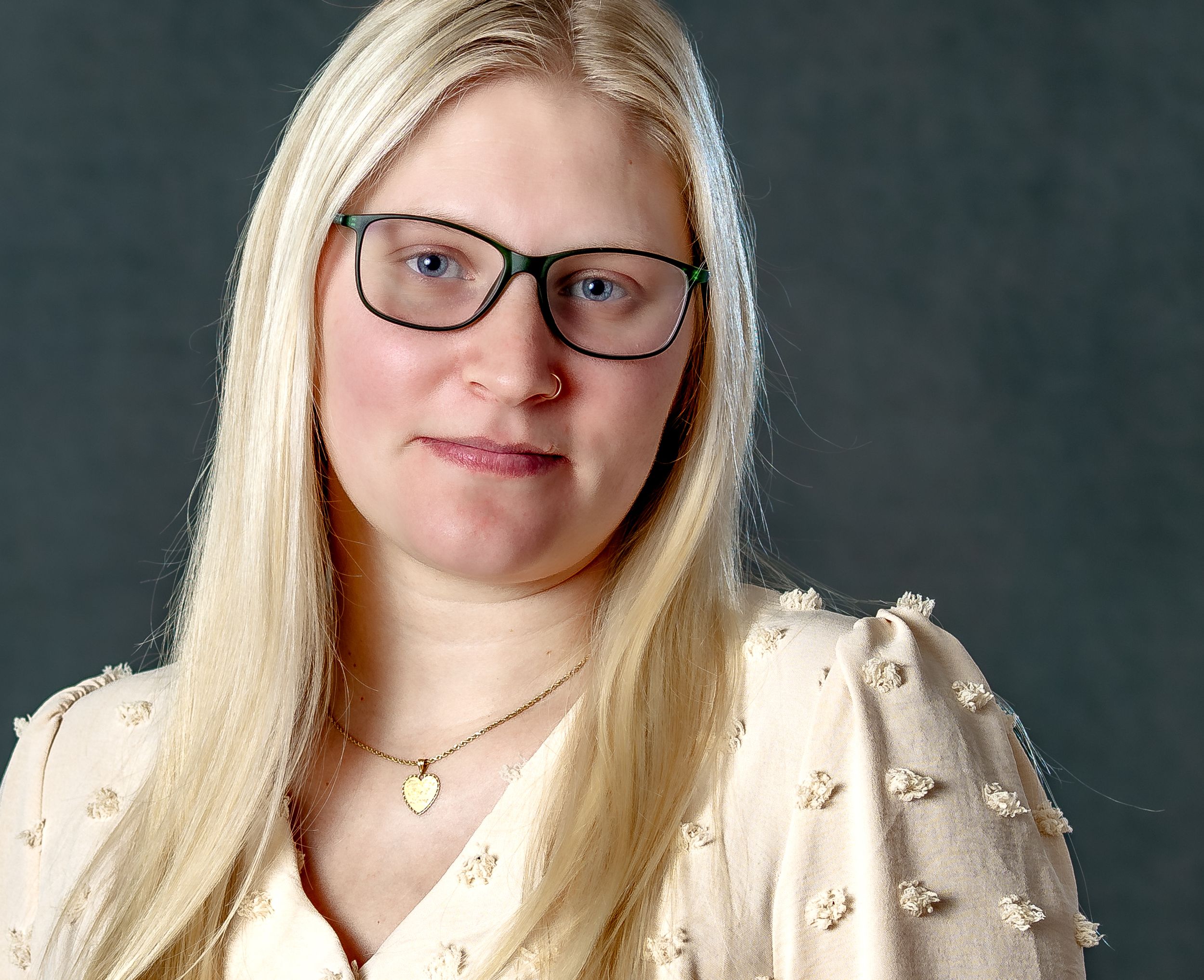 Portrait series showing someone in a cream colored top with long blonde hair against a dark background.