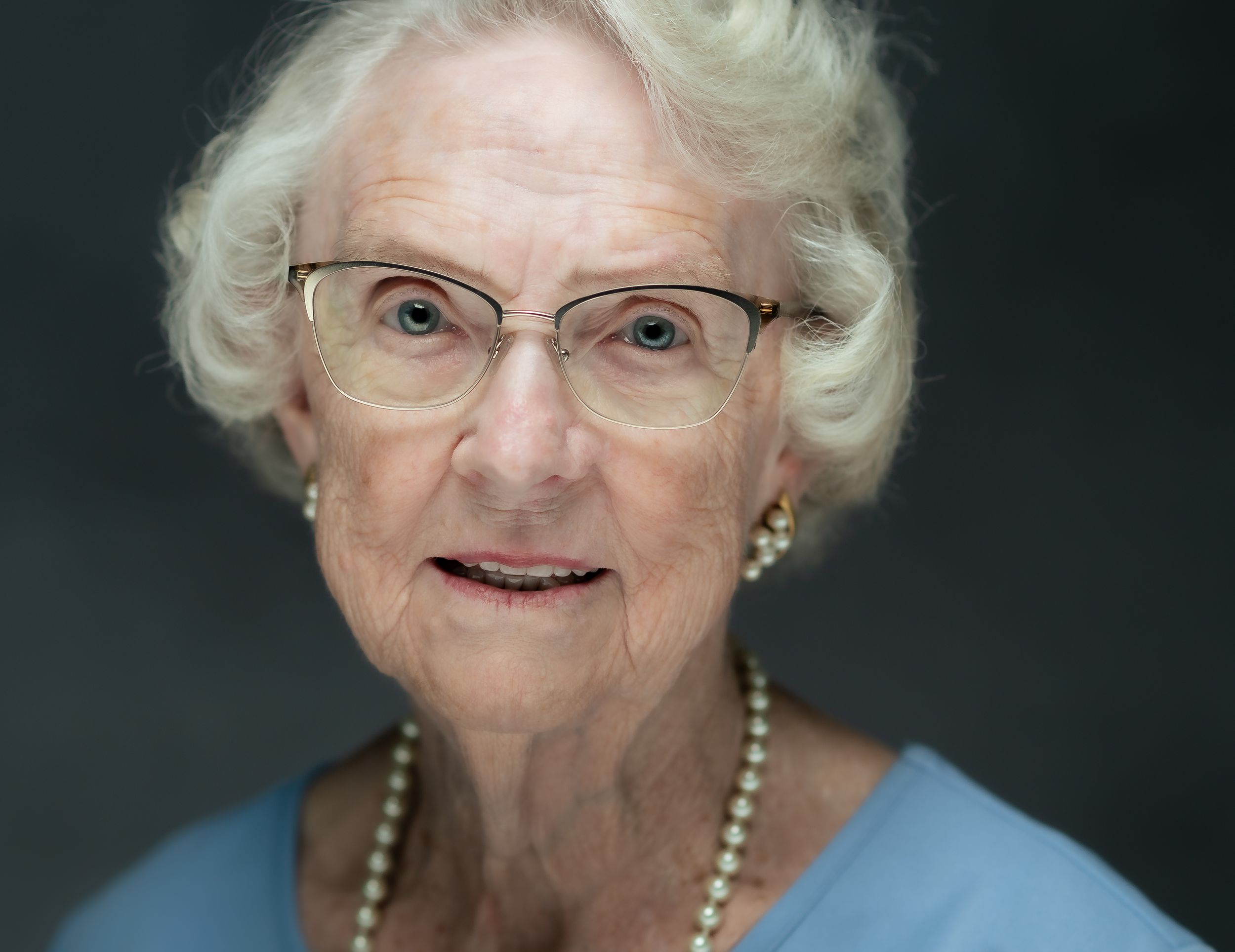 Sequence shows expressive facial gestures from profile to front view, with pearl necklace and glasses visible in the lighting.