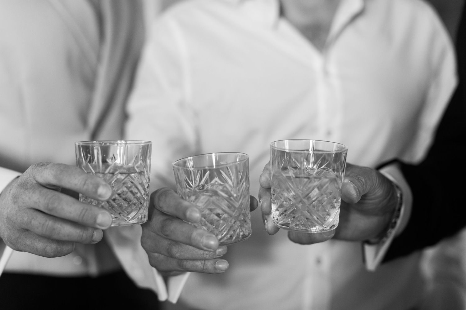 Three vintage cut crystal glasses being held together in a celebratory toast gesture by groom, brother and dad Pauntley Court wedding
