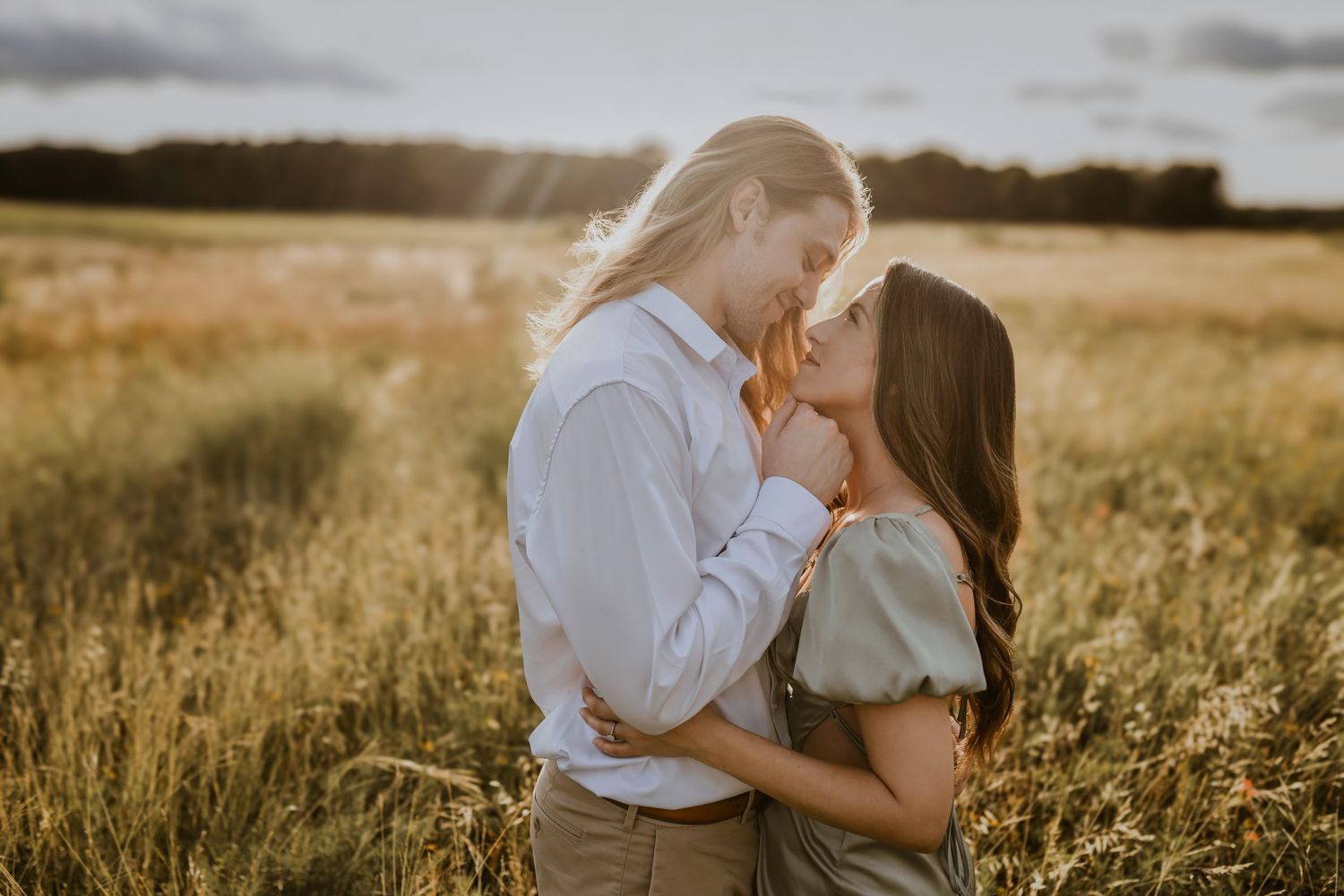 Tender kiss between couple surrounded by golden prairie