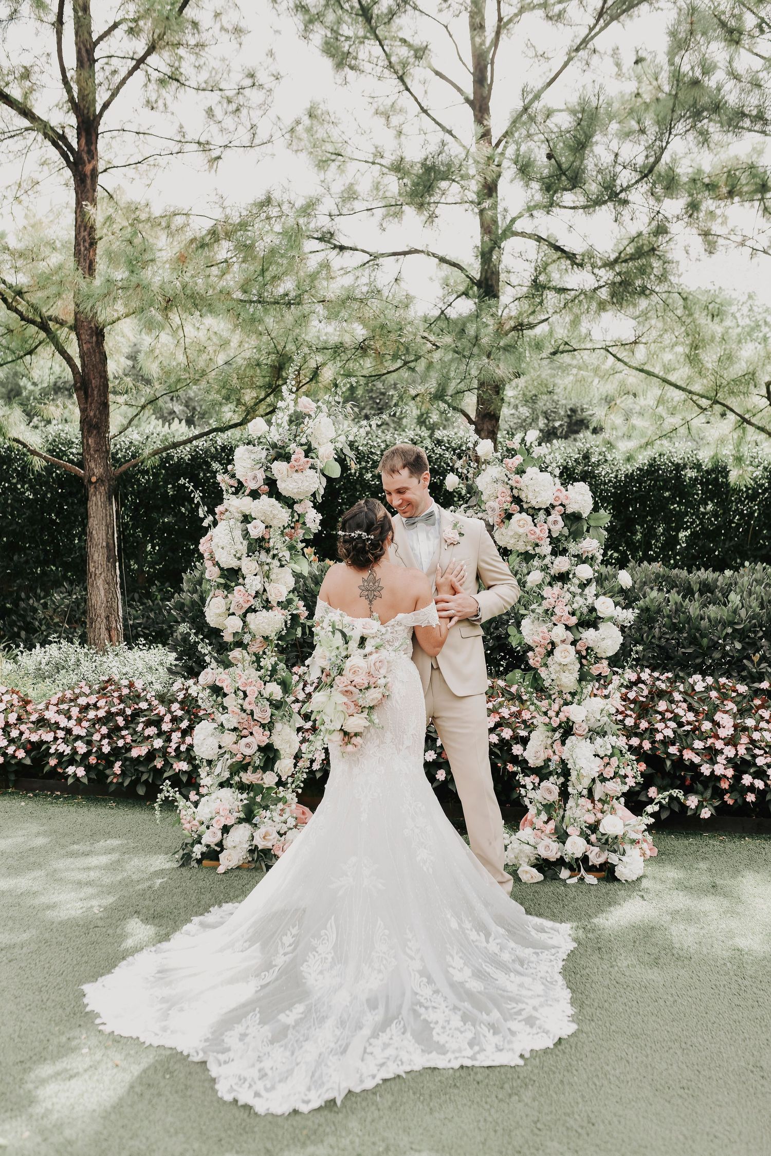 Groom in beige summer suit kissing bride at golden hour