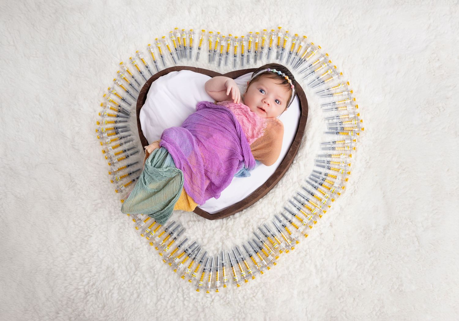 A small wooden bed filled with fur bedding and decorated with bright yellow sunflowers against a rustic backdrop.