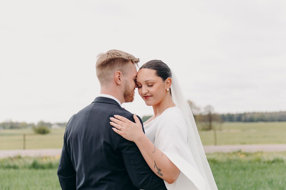 A couple shares an intimate moment together during their outdoor wedding ceremony in a serene rural setting.
