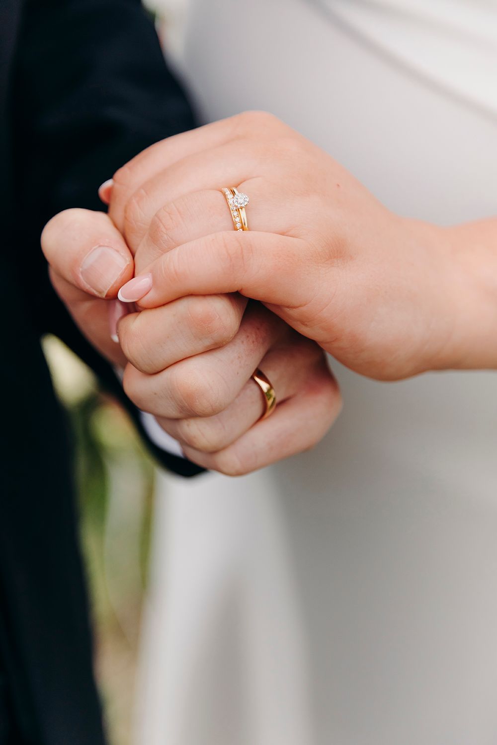 Close-up shot of newlyweds' hands showing gold wedding bands and a diamond engagement ring.