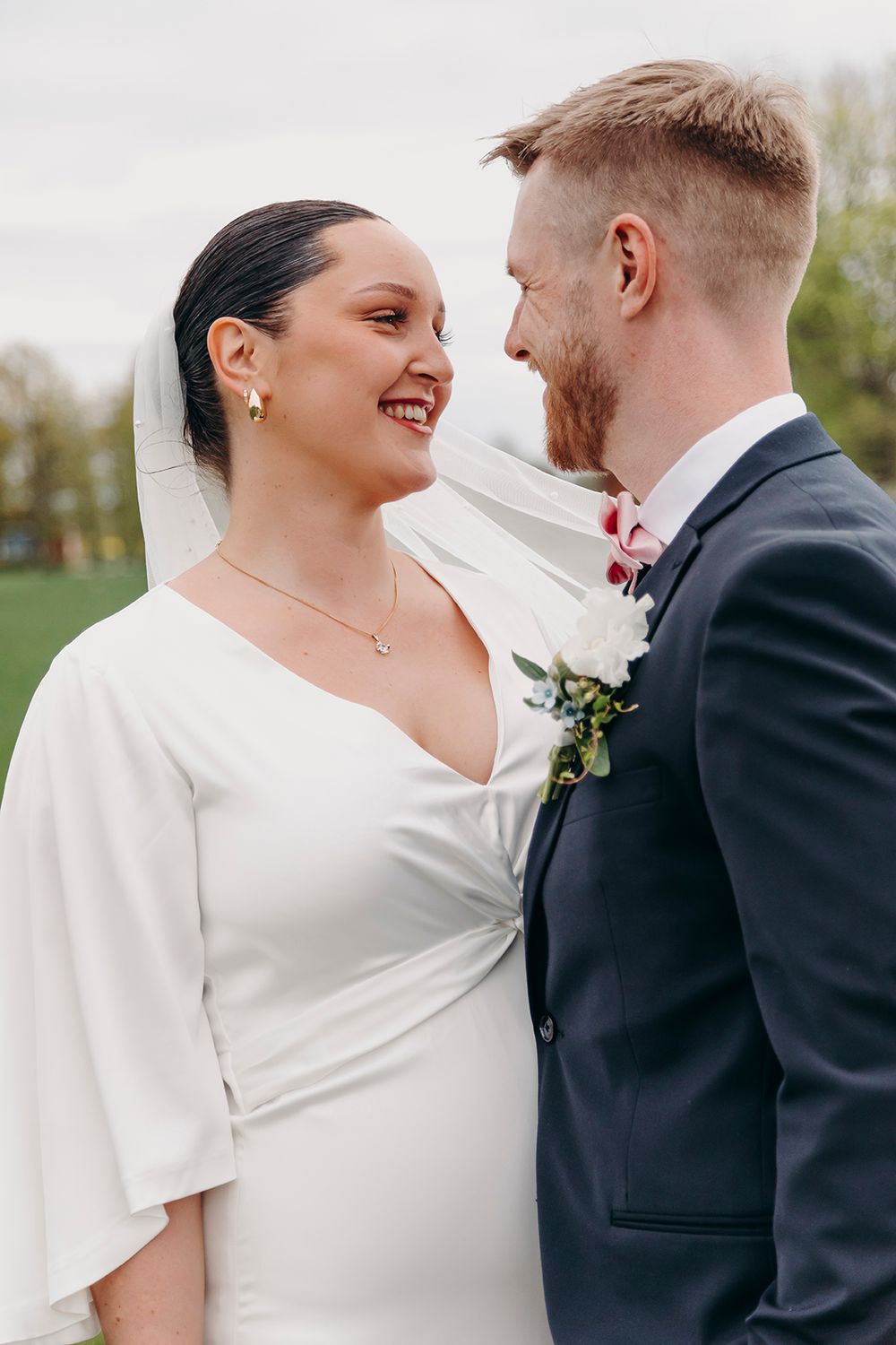A happy newlywed couple shares a joyful moment together outdoors during their wedding photoshoot.