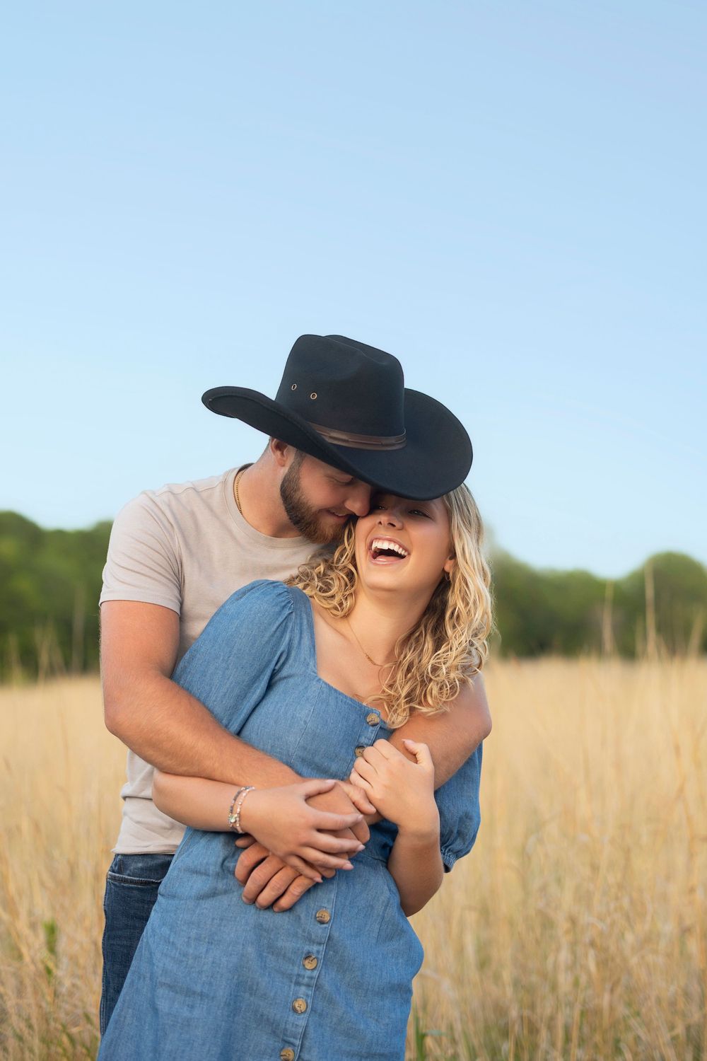 Couple sharing a tender moment in a golden wheat field on a sunny day.