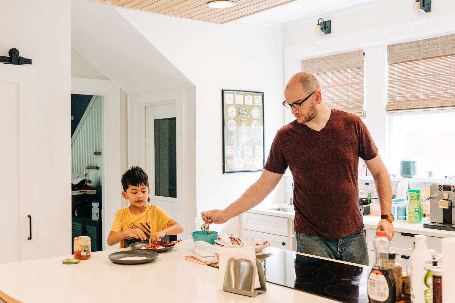 Two people prepare food together in a bright modern kitchen with white walls and wood accents.