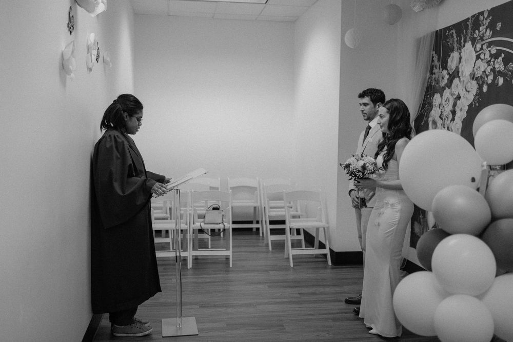 A black and white photo capturing a behind-the-scenes moment with decorative balloons in an indoor venue.