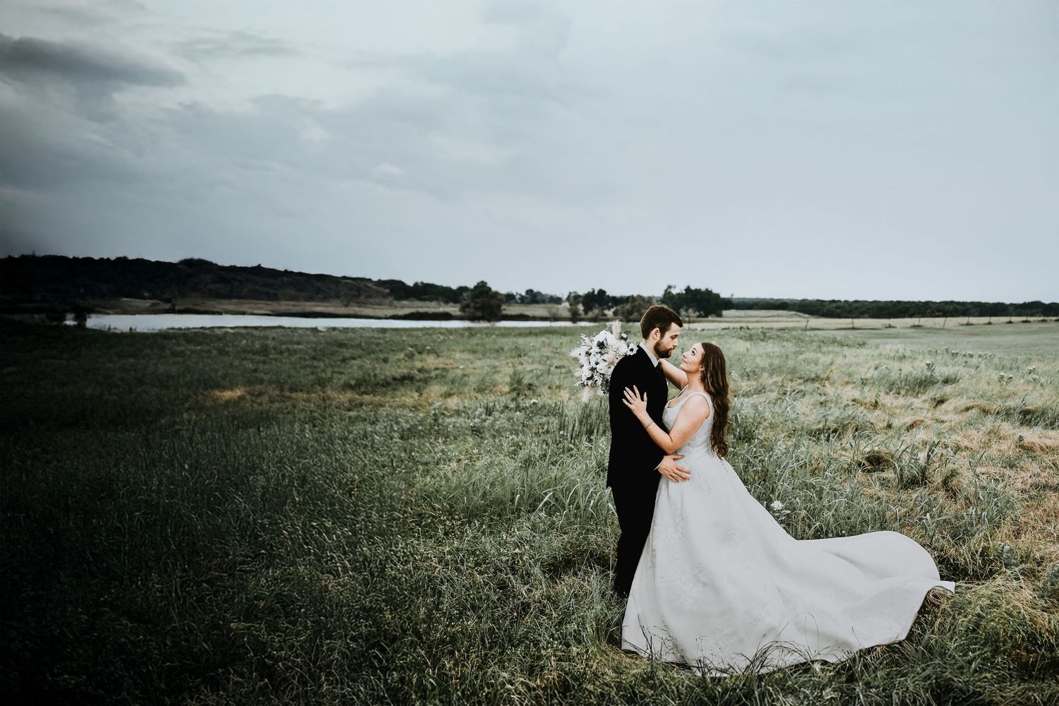 Bride and groom walking hand in hand through golden Texas field at sunset