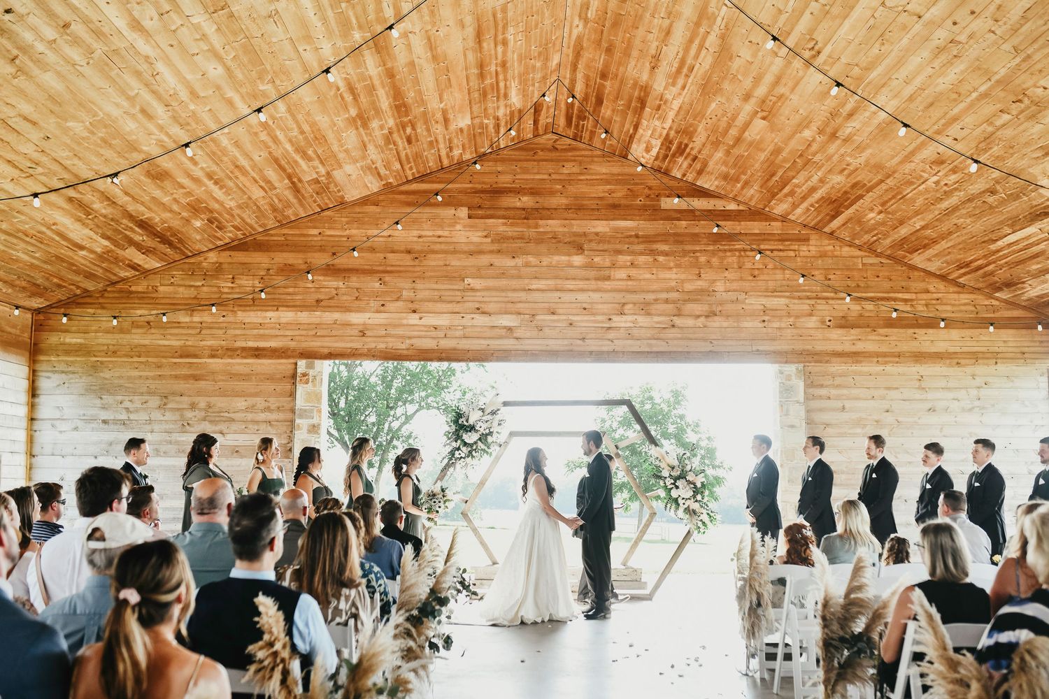 Outdoor wedding ceremony under rustic barn pavilion at The Madelyn
