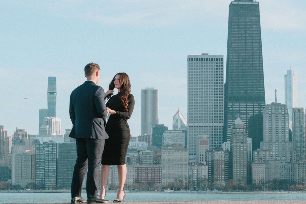 Two people stand together overlooking Chicago's skyline with Lake Michigan and iconic John Hancock building in view.