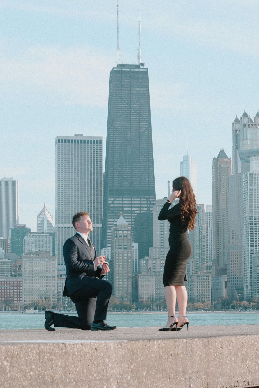 A couple gets engaged with the iconic Chicago skyline and John Hancock building in the background.