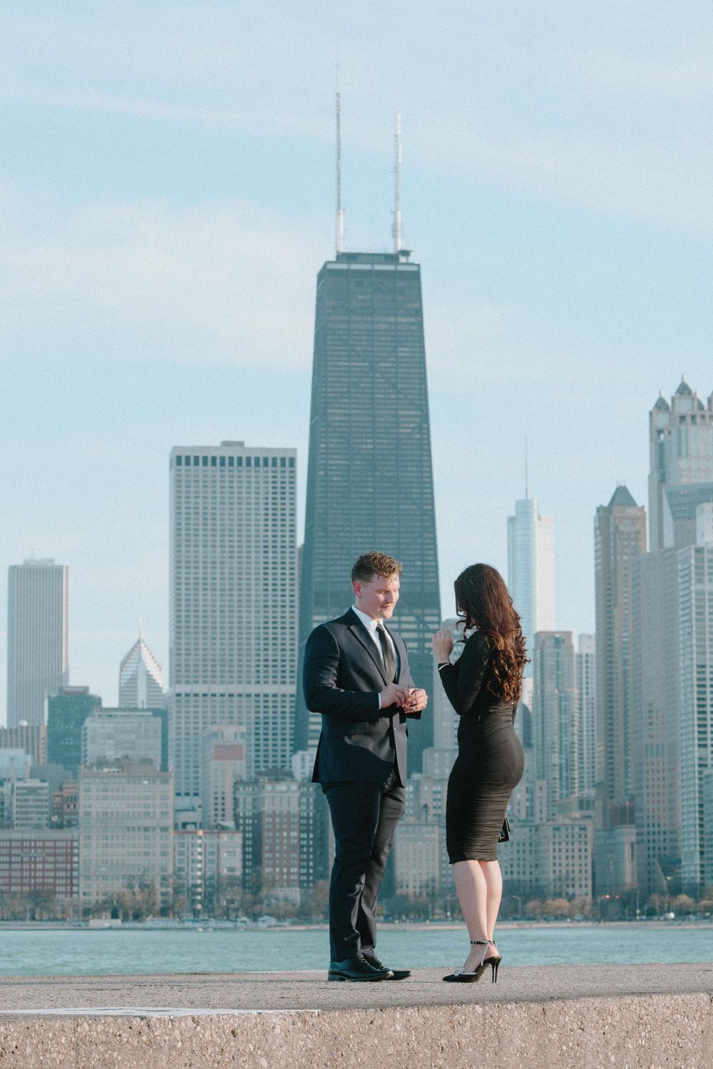 A couple shares a special moment against the iconic Chicago skyline with the John Hancock building in view.