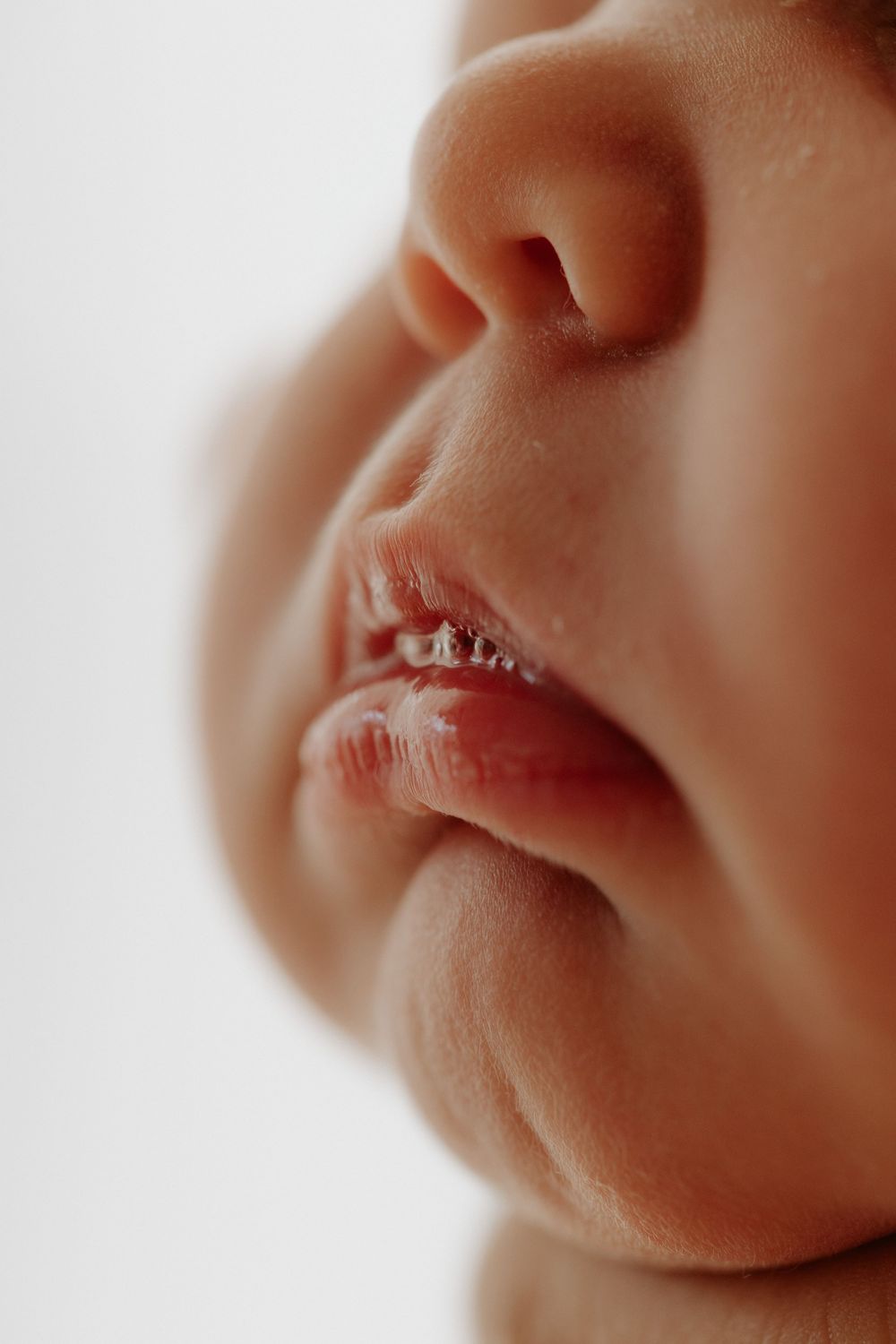 A series of five close-up macro photographs showing infant lips in warm soft lighting.