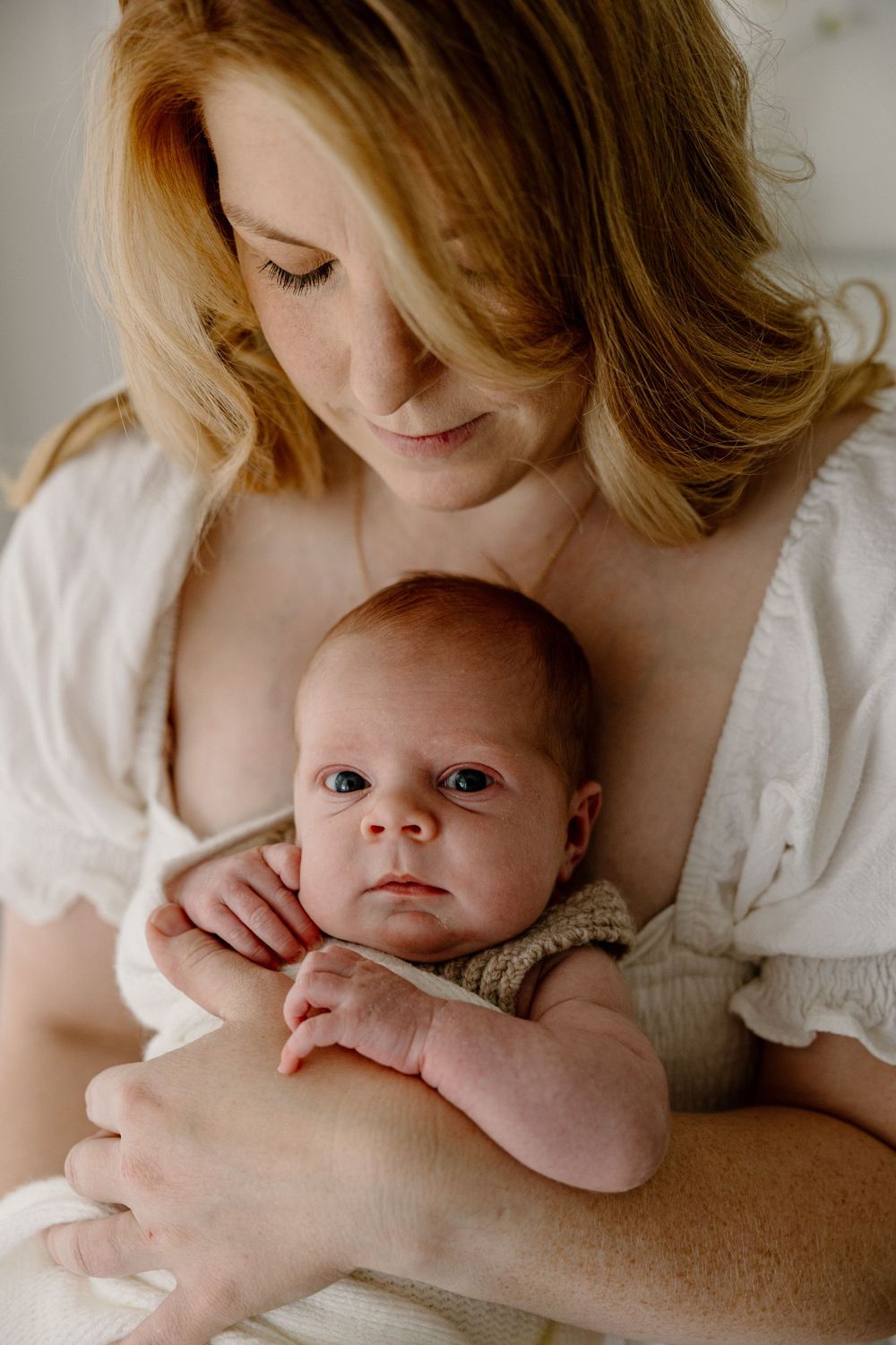 A series of tender moments captured between mother and newborn baby in soft, natural light on white bedding.