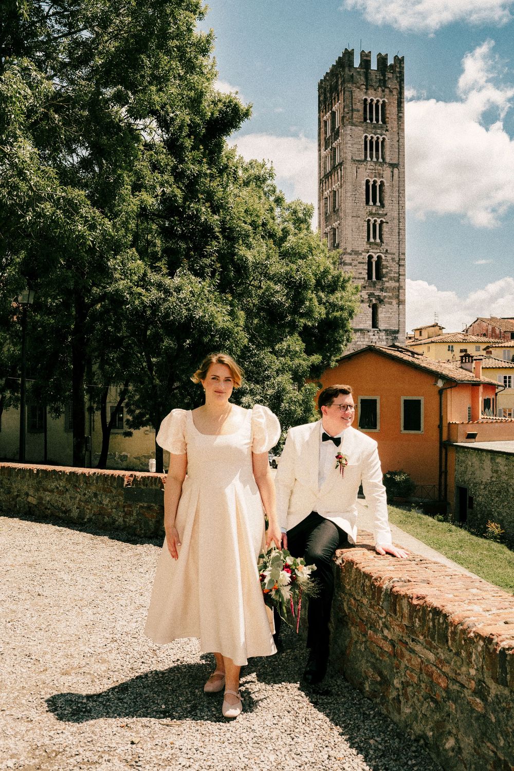 A couple takes wedding photos near a medieval stone tower in Tuscany.