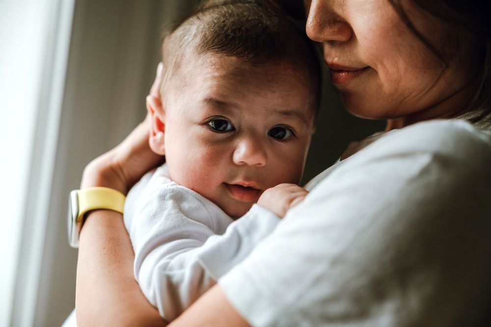 Reena and her newborn baby, William, embrace in a 100 days photography session in Washington, DC.