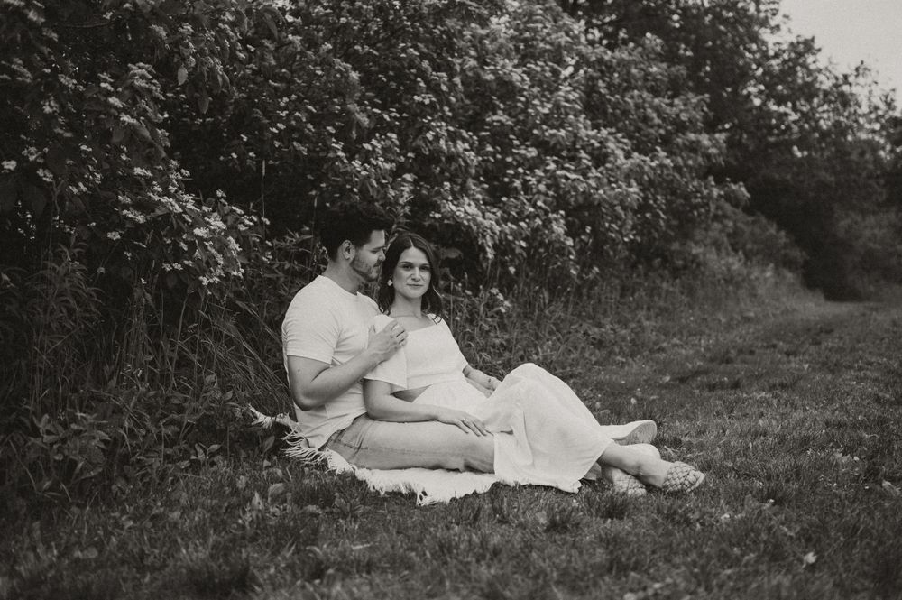 A black and white photo of a couple relaxing on a picnic blanket amid nature.