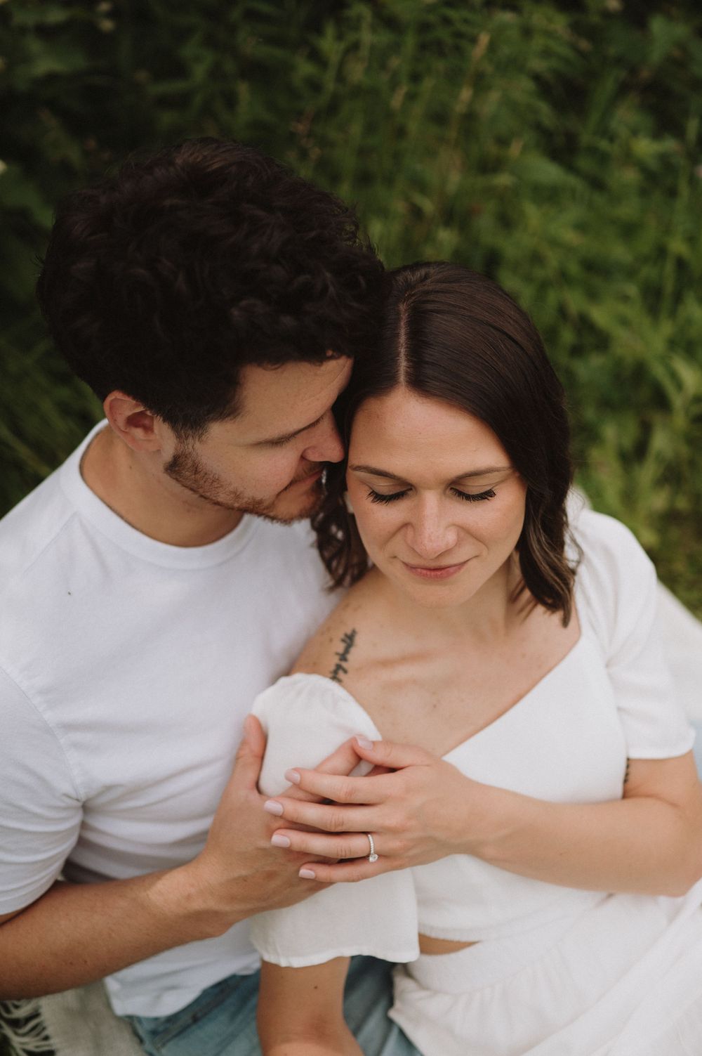 An intimate close-up photo of a couple sharing a tender moment outdoors.
