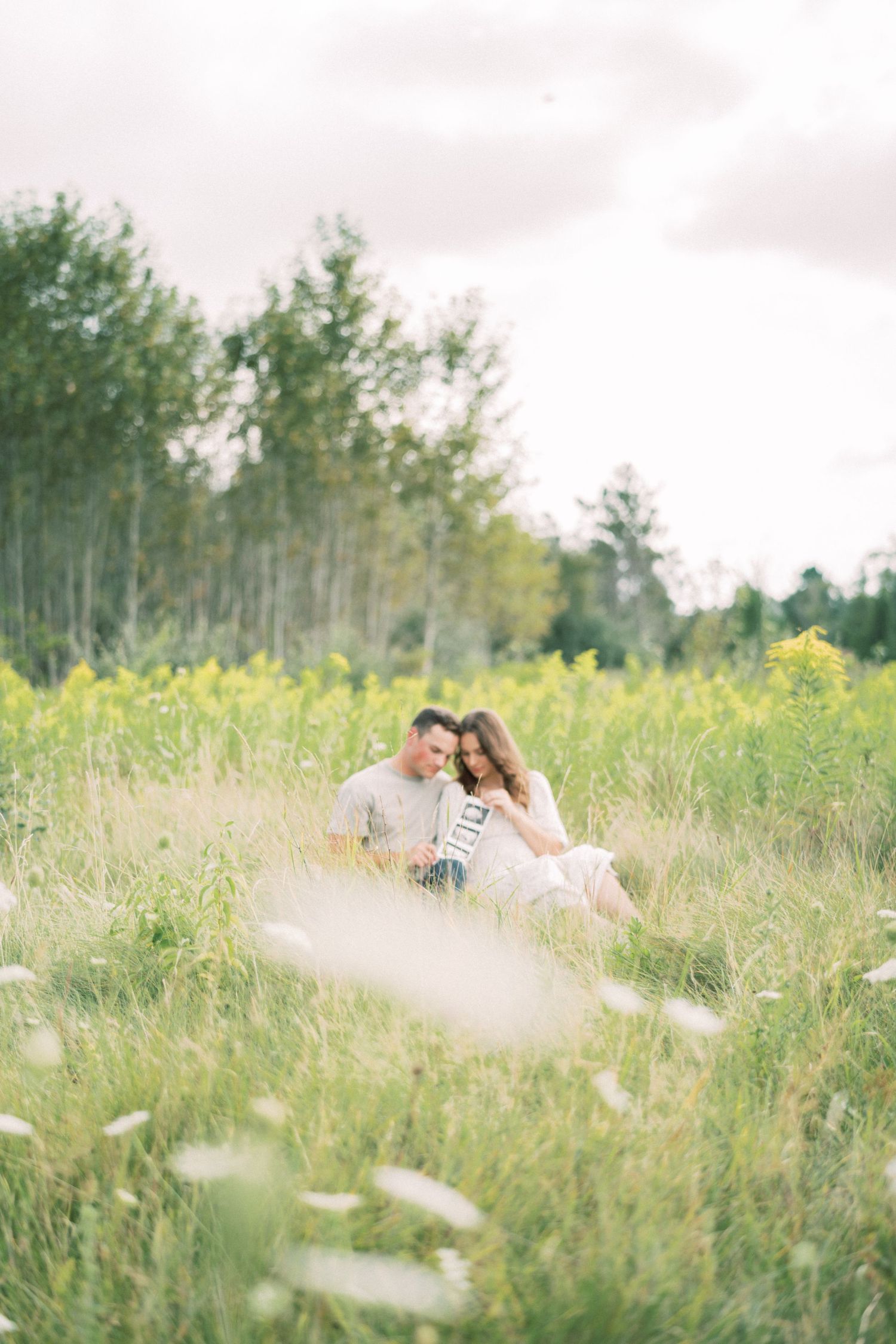 Romantic couple embracing in dreamy wildflower field during sunset photoshoot.