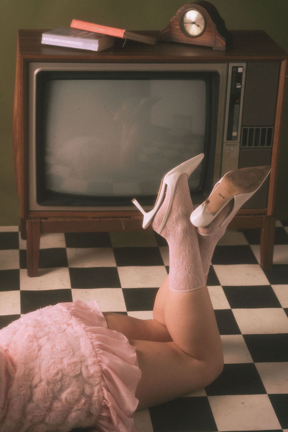 Retro television set with pink high heels and checkered floor in vintage-style composition.