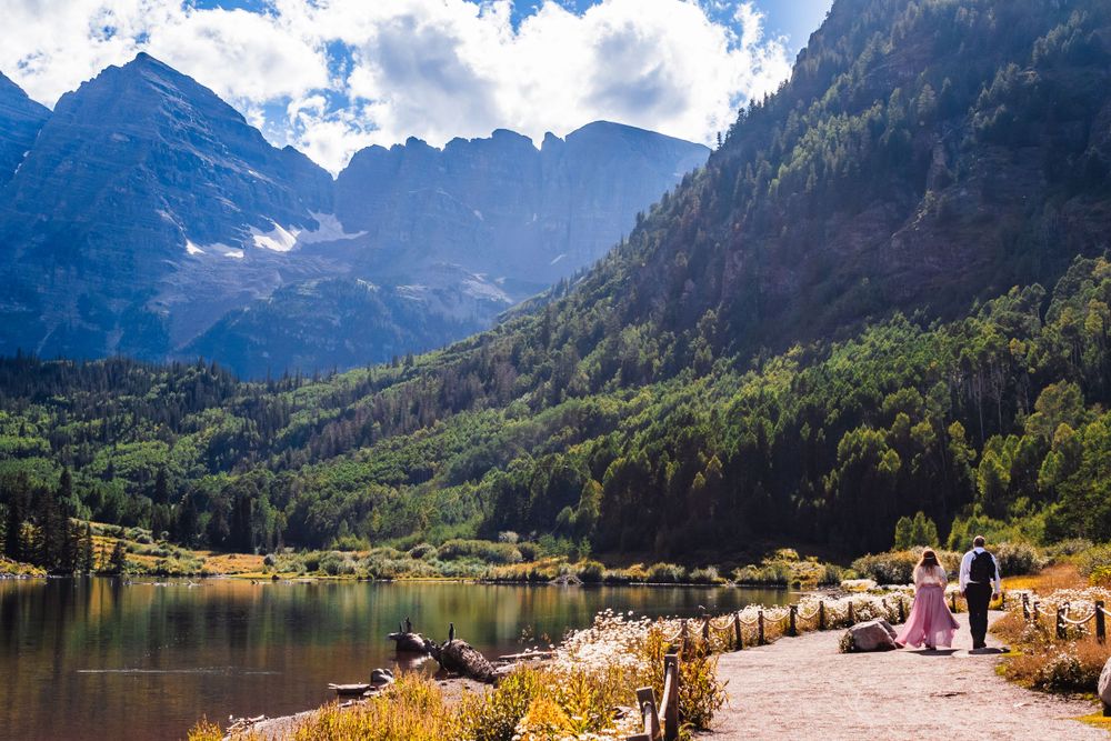 Scenic mountain trail along an alpine lake with distant peaks and hikers enjoying the view.