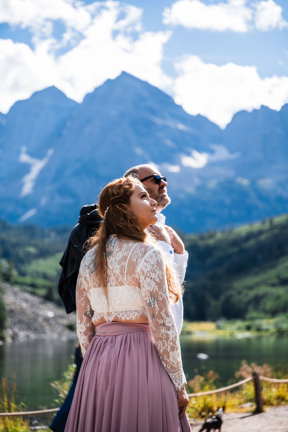 A romantic mountain photoshoot with a couple embracing by an alpine lake in majestic scenery.