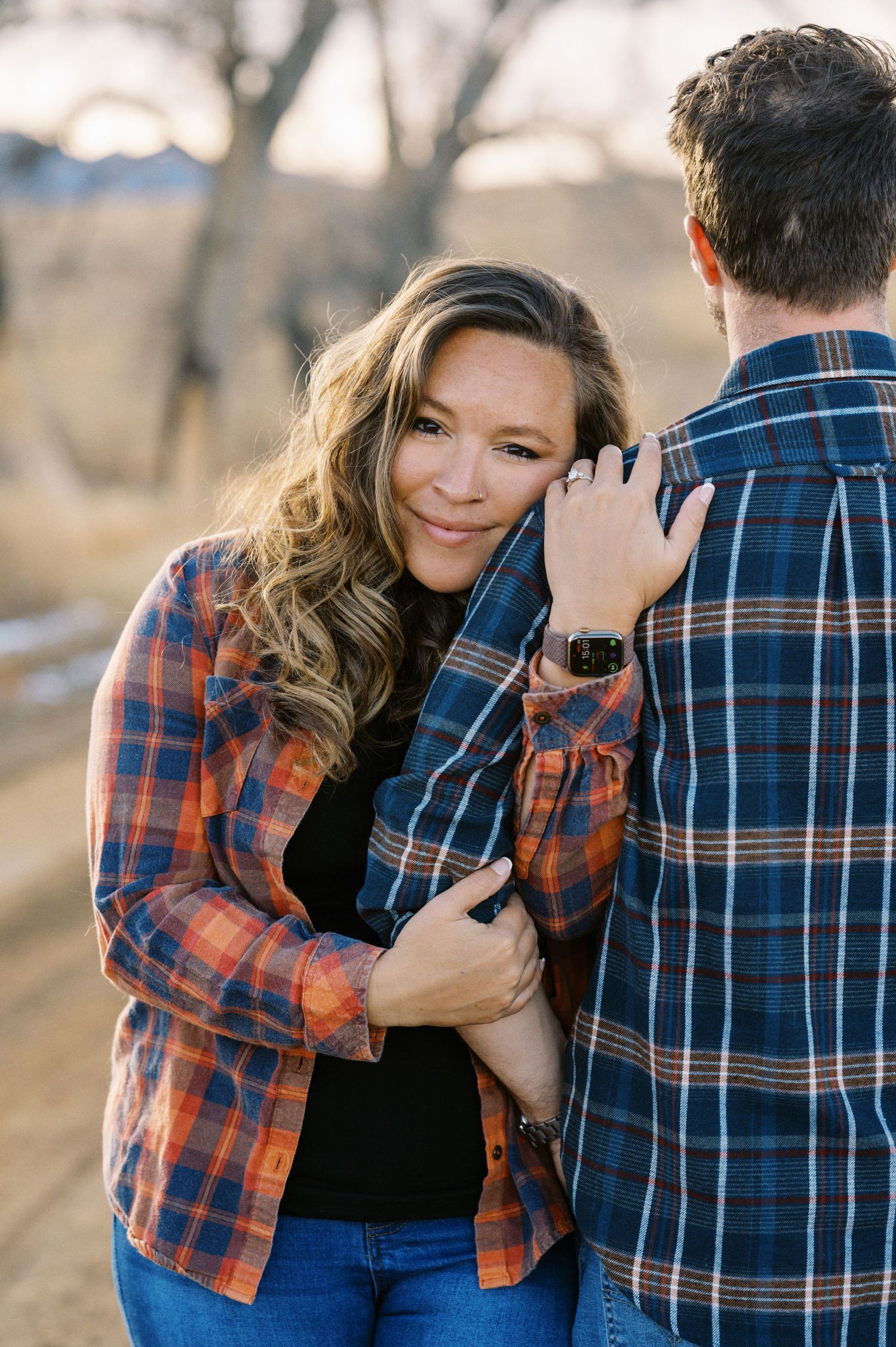 A couple shares an intimate moment while wearing coordinating plaid shirts on a countryside path.