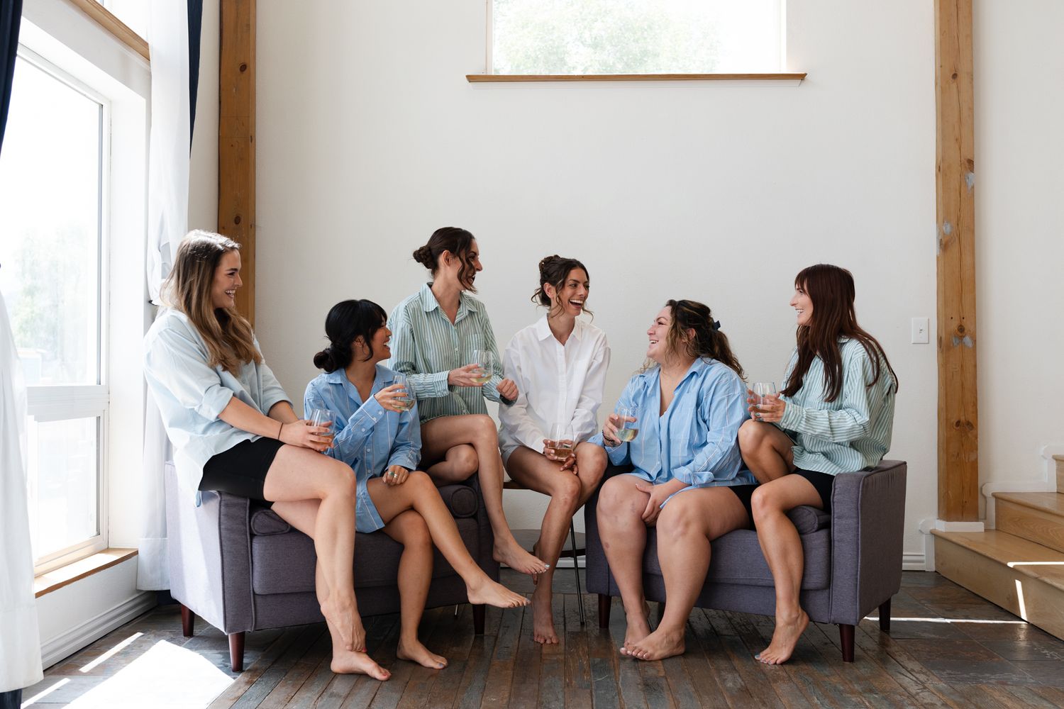 Group of friends sitting together on gray couch wearing matching blue shirts and shorts.
