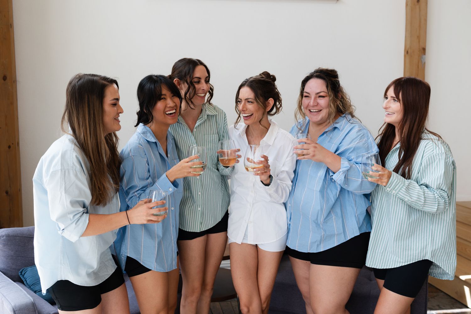 Friends in matching denim shirts sharing celebratory drinks and laughter.