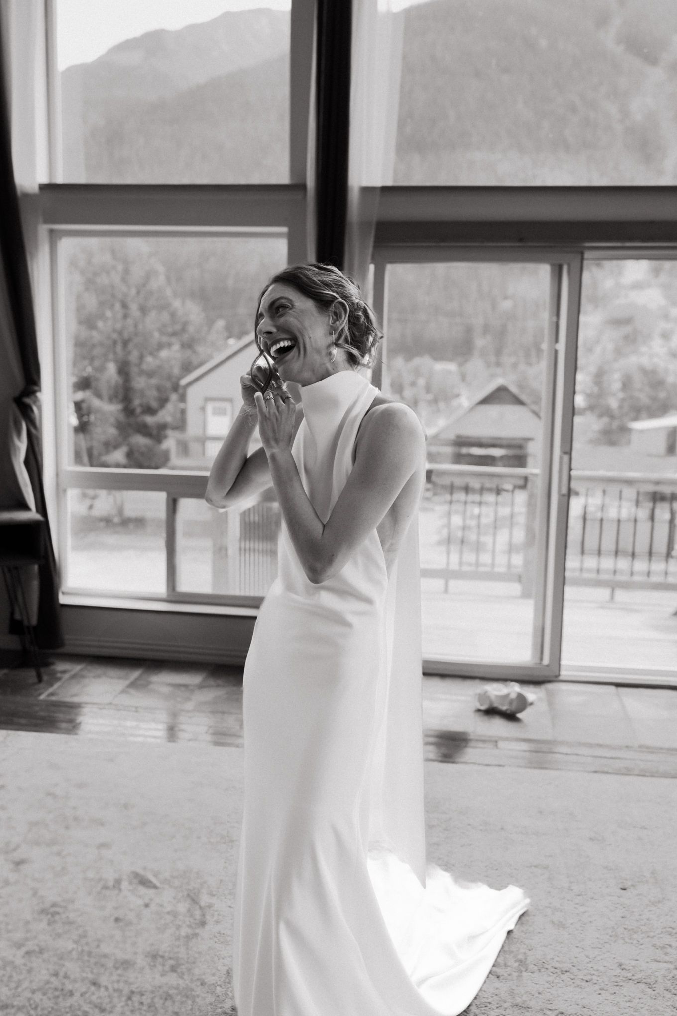 Black and white portrait of emotional bridal moment with mountain scenery in background.