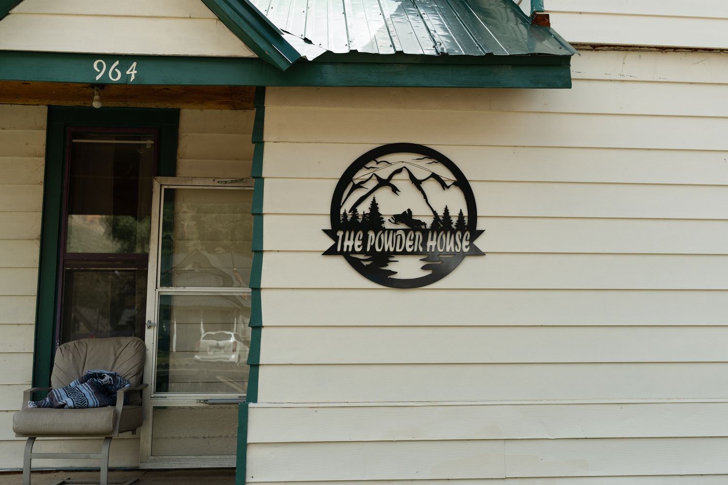 Mountain-themed logo sign on white exterior wall of building number 964.