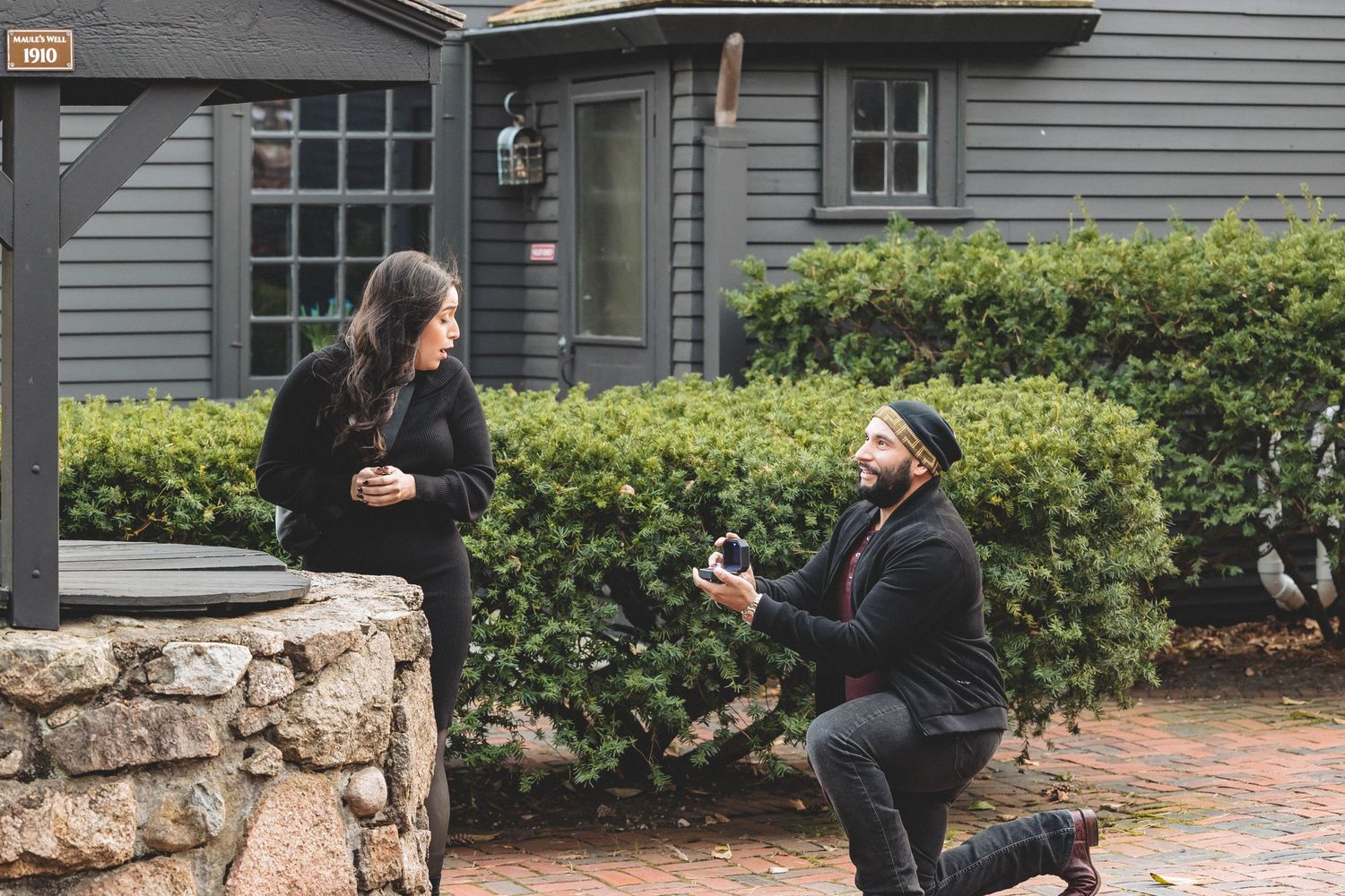A marriage proposal taking place in front of a classic New England style home.
