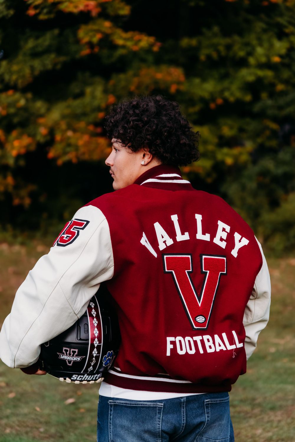 Back view of Valley Football varsity jacket with number and text shown against fall trees.