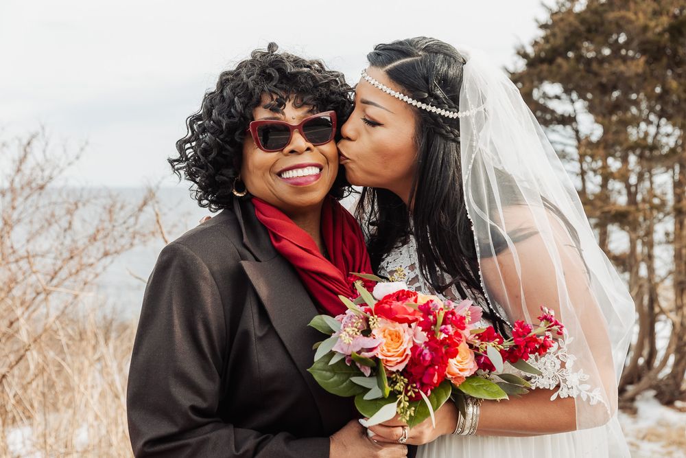 A joyous moment at an outdoor winter wedding celebration with a colorful red and pink bouquet.