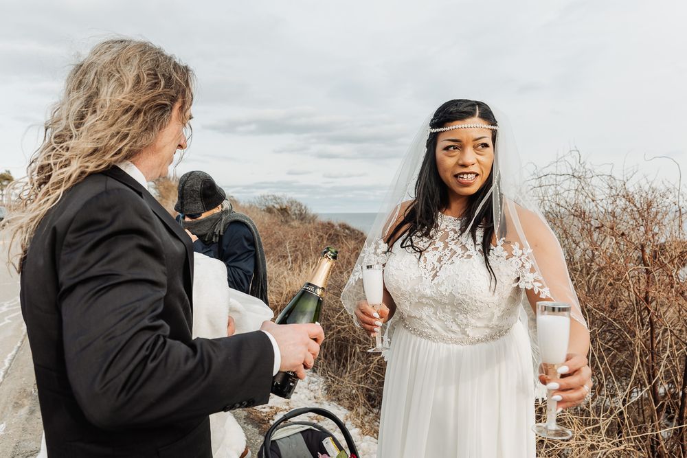 A couple celebrating an outdoor wedding ceremony on a mountain landscape in winter with overcast skies.