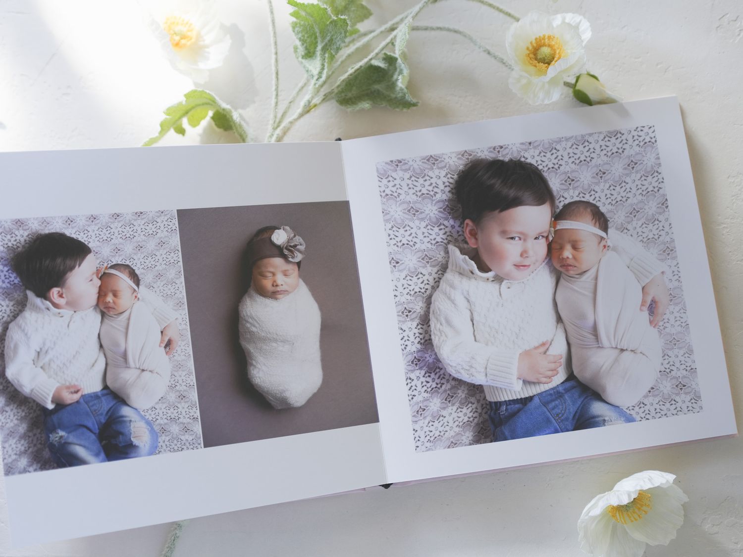 Professional photo album spread showing siblings in coordinated white outfits.