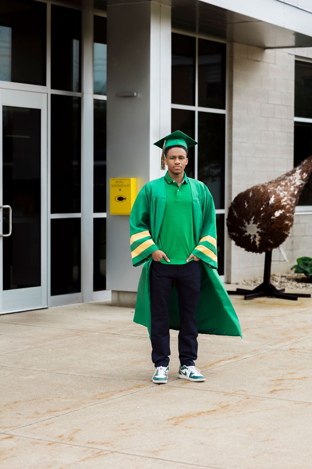 Coloma High School graduate celebrating cap and gown milestone outdoors