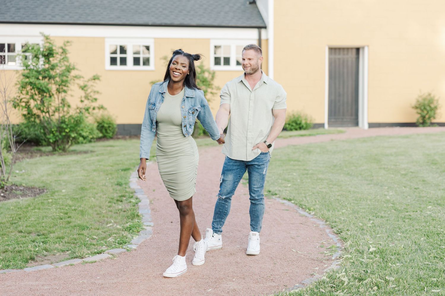 A couple walking together on a garden path, with one wearing a mint green dress and white sneakers.