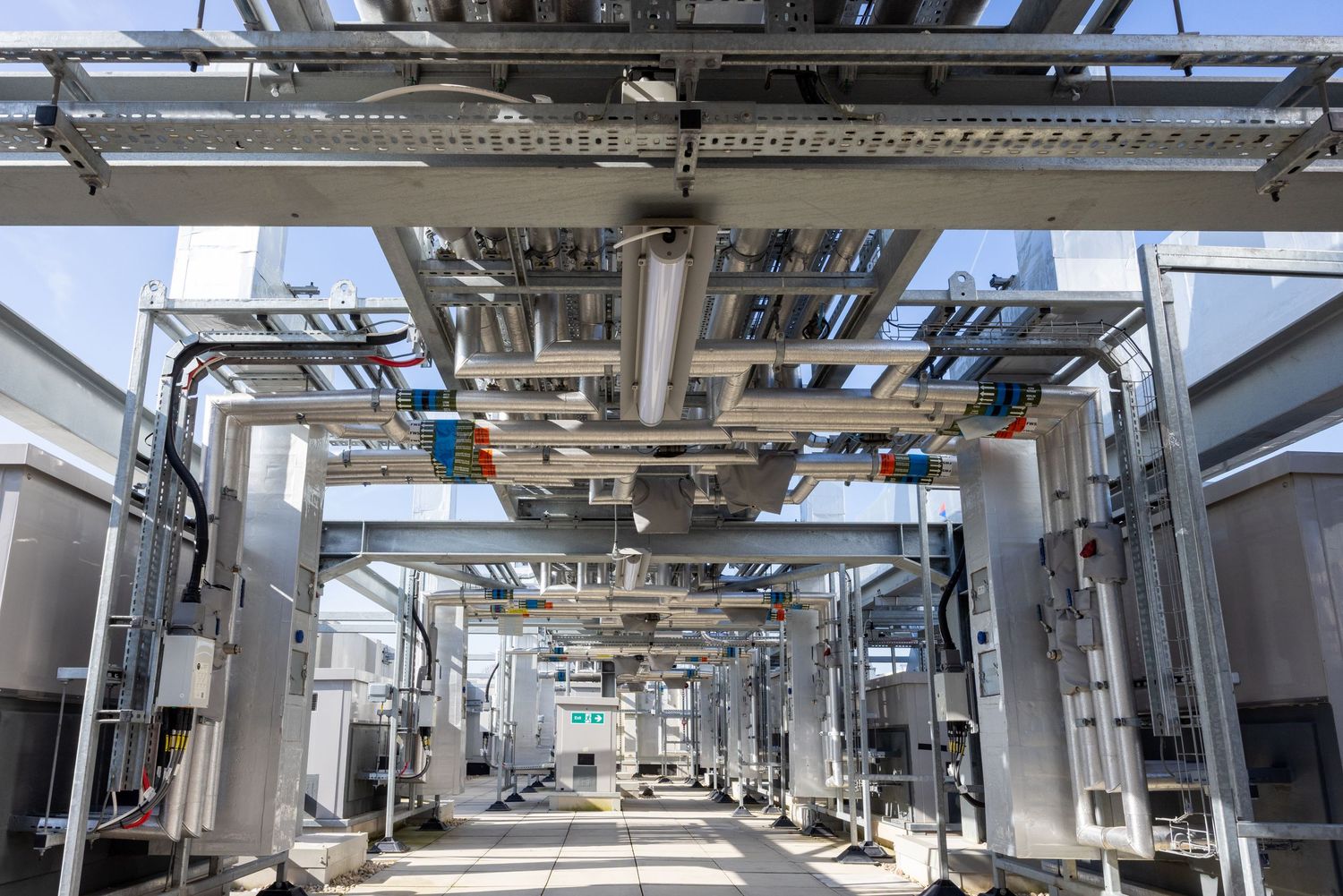 Industrial mechanical room with complex overhead piping and equipment installations.