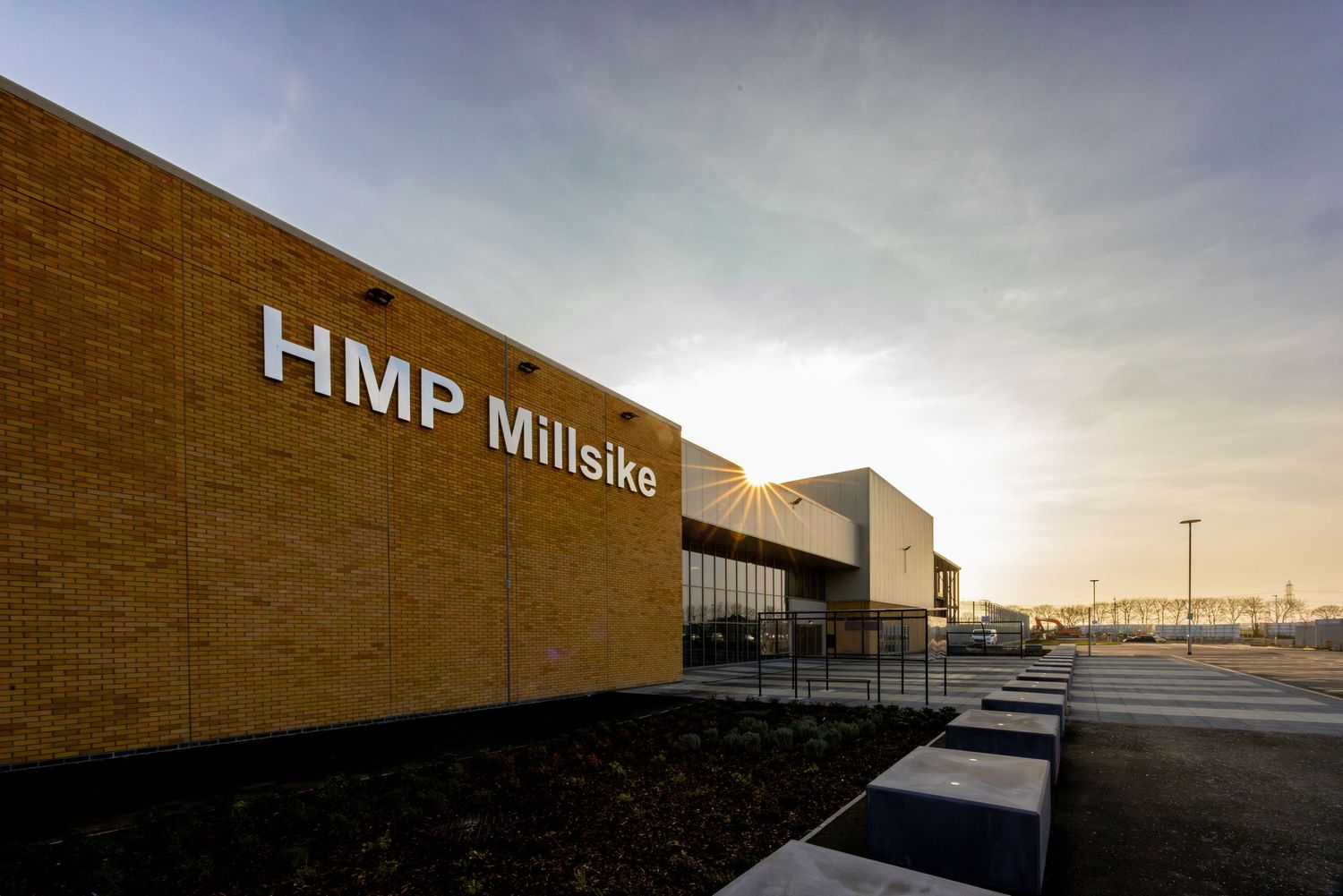 Exterior view of HMP Millsike building with brick facade at dusk.