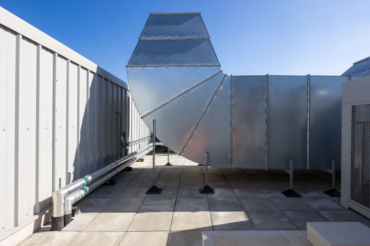 Reflective metal HVAC equipment and ductwork installed on commercial rooftop.