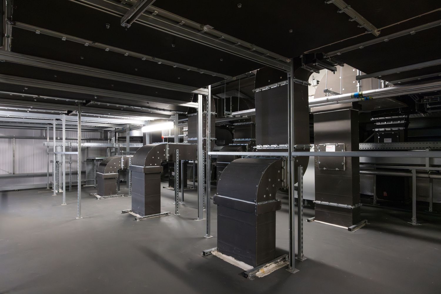 Dark industrial space with equipment racks and mechanical installations on raised platforms.