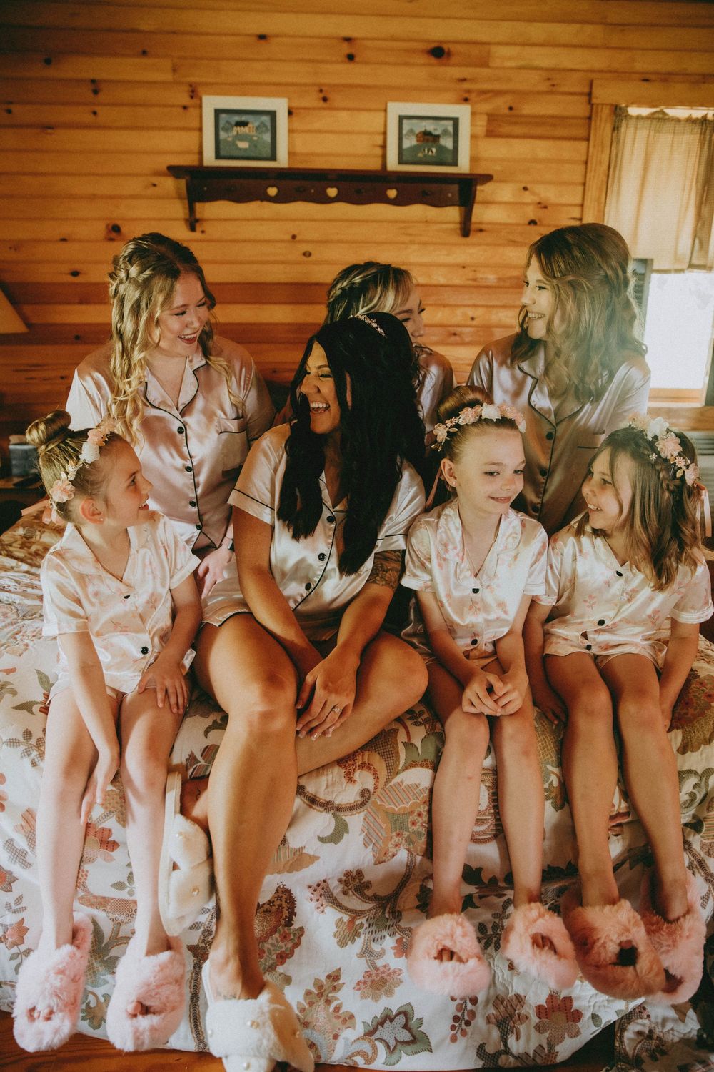 A group wearing matching pink robes sits together on a wooden bench in a rustic log cabin interior.