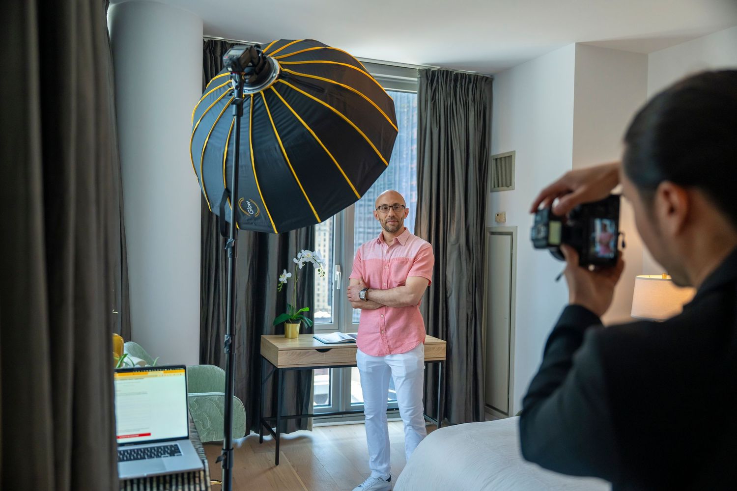 Professional studio portraits being captured with lighting equipment and black umbrella reflectors in a modern interior space.