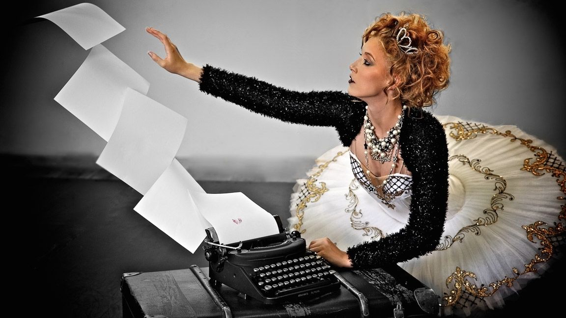 A glamorous ballerina in a black and white outfit dramatically throws papers from a vintage typewriter