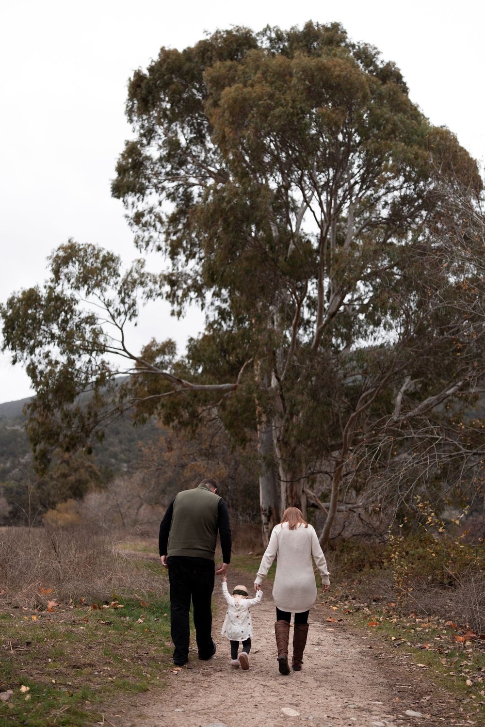 Family walking together on a nature trail surrounded by eucalyptus trees.